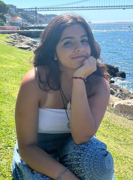 Fotografia da Rafaela Lontro a sorrir, sentada na relva junto ao rio.